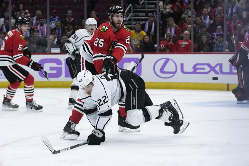 Los Angeles Kings left wing Kevin Fiala (22) and Chicago Blackhawks defenseman Jarred Tinordi (25) chase the puck during the first period of an NHL hockey game Thursday, Nov. 3, 2022, in Chicago. (AP Photo/Matt Marton)