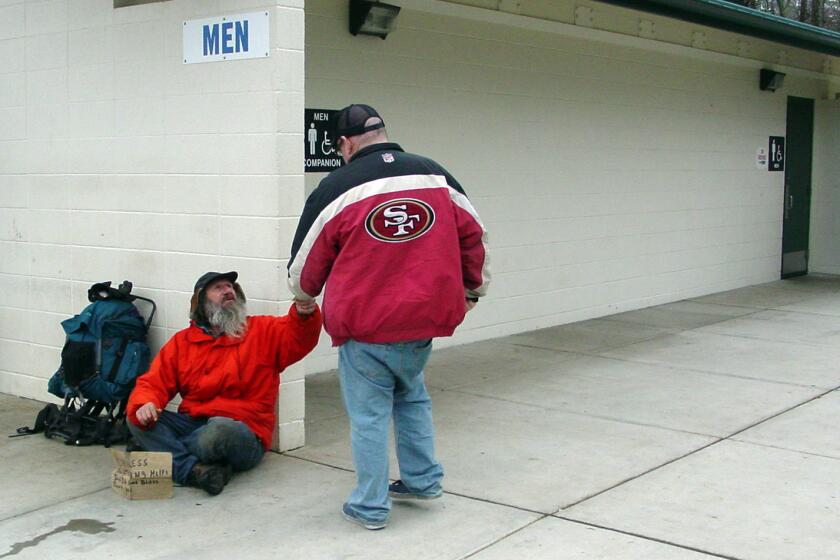 In this photo taken Jan. 3, 2011, Keith Merrill is given a donation by Jim Lawrence at the Interstate 5 Manzanita rest area north of the Merlin, Ore. Merrill, who is a longtime frequent panhandler at the rest area, said he is careful about how he seeks handouts, and that he has constitutional rights to free speech. (AP Photo/ Grants Pass Daily Courier, Shaun Hall)
