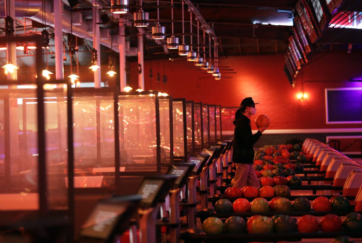 A man holds a ball in a largely empty bowling alley