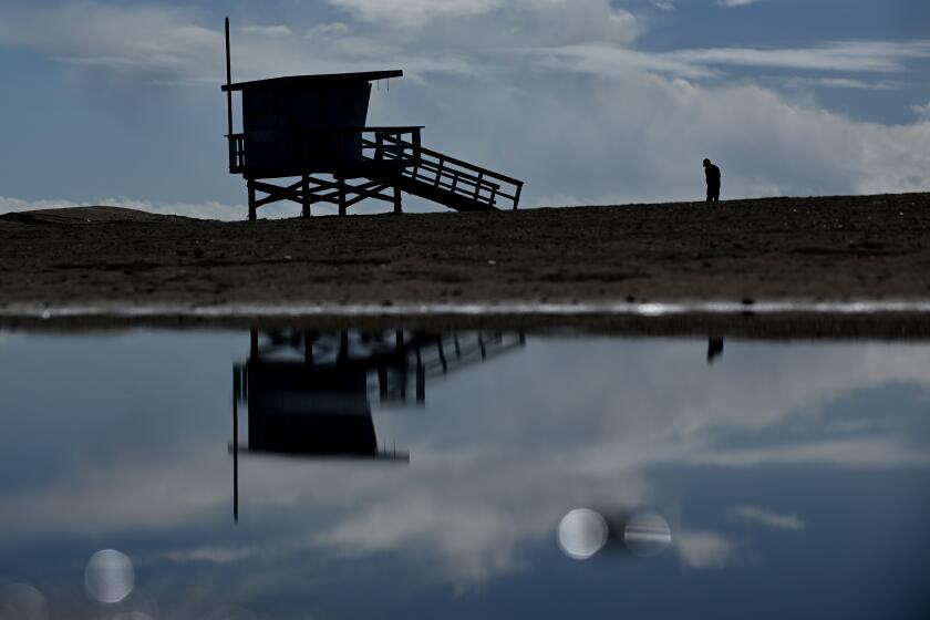 El Segundo, California February 23, 2023-A man is reflected in a puddle at Dockweiler State Beach during a break in the storm Thursday. (Wally Skalij/(Los Angeles Times)
