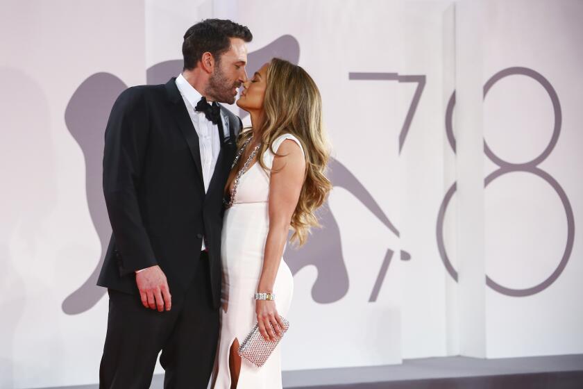 Ben Affleck wearing a suit and almost kissing Jennifer Lopez in a white gown at a red carpet event