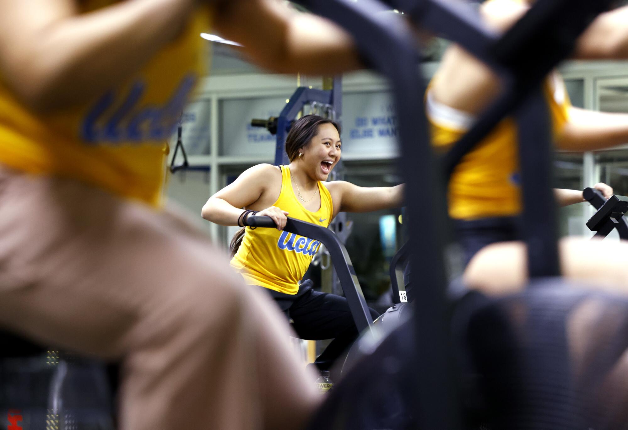 Emma Malabuyo laughs while riding an exercise bike alongside teammates.
