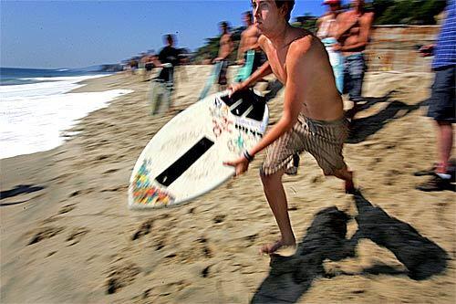 On the beach in South Laguna, Tyler Lopez, 21, charges the surf with skimboard at the ready. Behind him, other skimboarders watch approaching breakers looking for their next ride. Bill Bryan, left, one of the world's top skimmers, goes for a midair board grab.