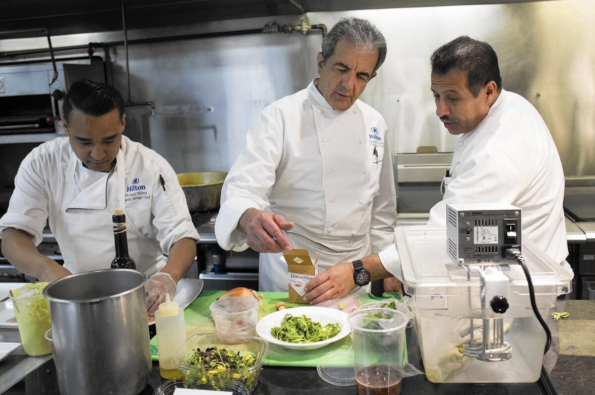 Executive Chef Frederic Castan, center, works with Juan Lopez, right, executive sous chef, and Michael Yniesta, garde manger chef, as they prepare a meal at the Hilton Anaheim Hotel's Mix Restaurant.