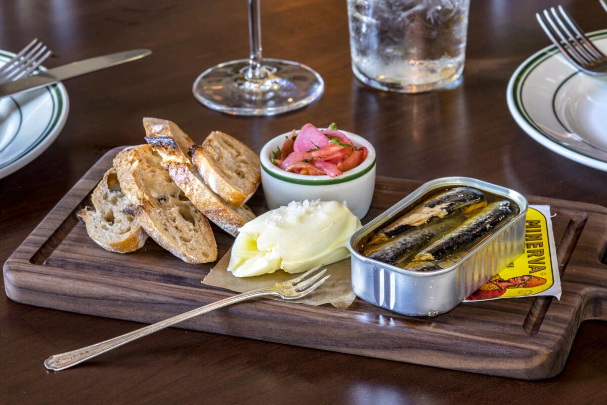 A tin of fish served with bread and pickled vegetables.