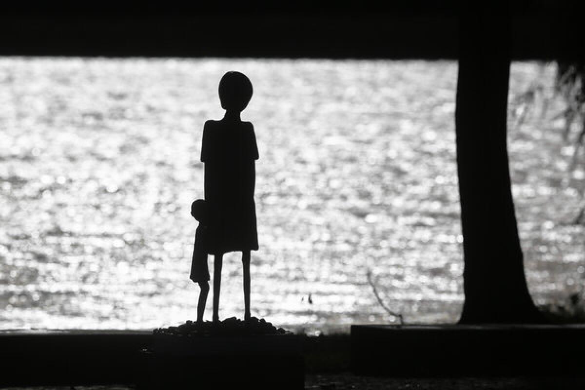 A sculpture of a woman and a child is silhouetted against the water of Schwedsee lake at Nazi death camp Ravensbrueck. On Nov. 9, Germany remembers the 75th anniversary of the "Kristallnacht," the night Nazis coordinated a wave of attacks in Germany and Austria, smashing windows, burning synagogues, ransacking homes and looting Jewish-owned stores.