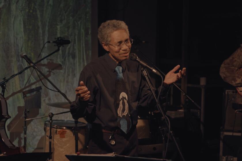 A musician at a microphone holds his hands out in the documentary "Keyboard Fantasies."