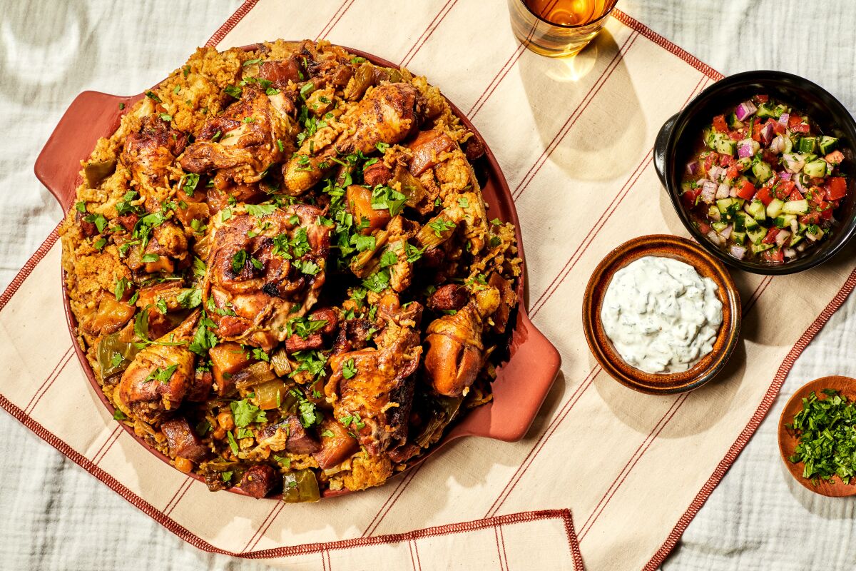 A pot holds a dish made of chicken and rice, with small bowls of condiments on the side.