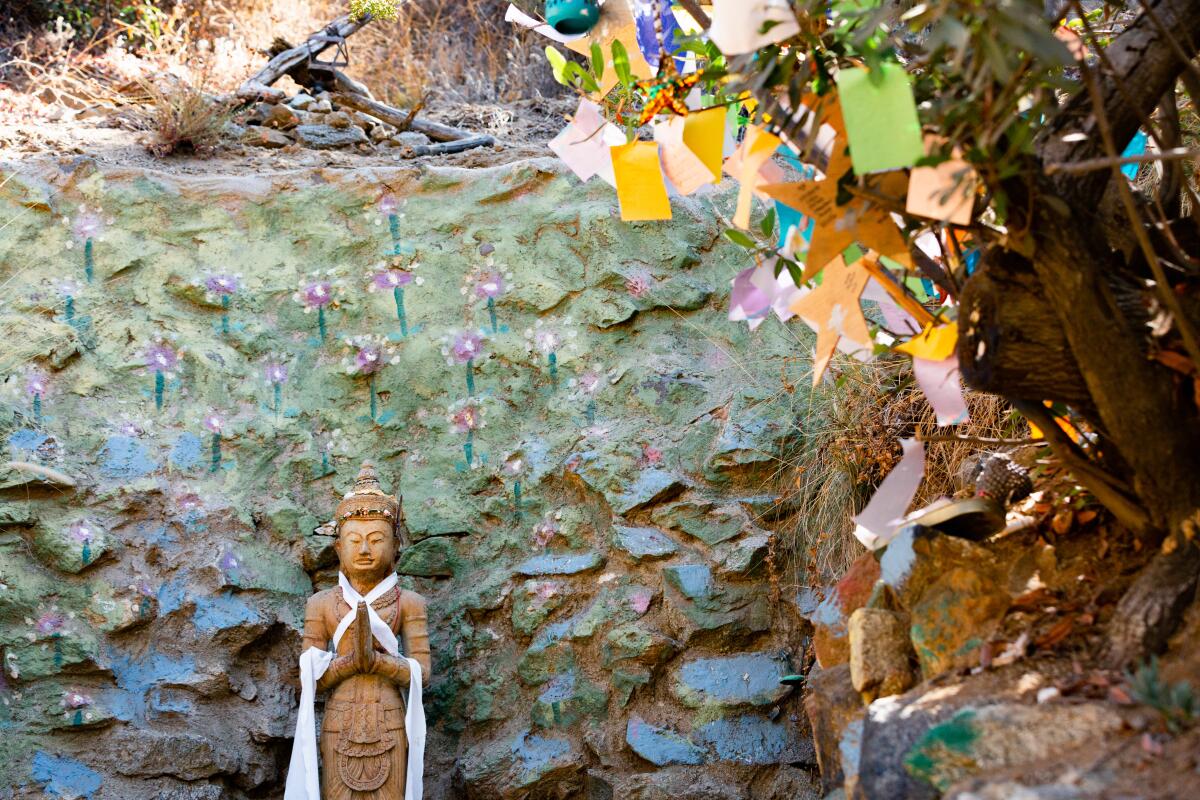 A buddha statue sits atop a stone staircase next to a tree 