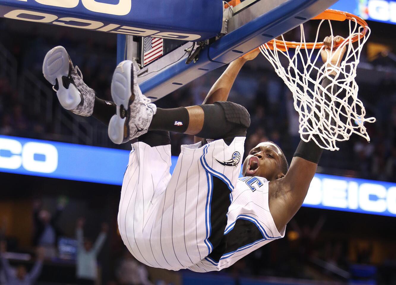 Magic guard Victor Oladipo hangs on the rim after throwing down a dunk in overtime to help seal a victory over the Lakers on Friday night.