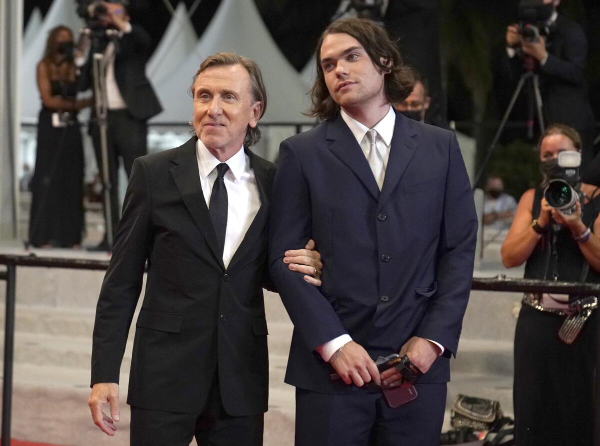 A father and son wearig suits as they pose for cameras at a movie premiere