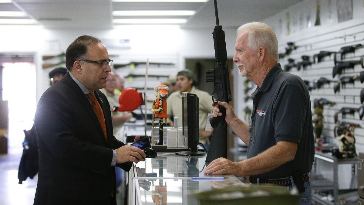 A sales associate shows a customer a semiautomatic rifle at Bullseye Sport gun shop in Riverside, Calif. on Dec. 9, 2015.