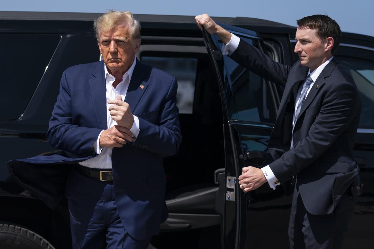 Former President Trump steps out of a vehicle. 