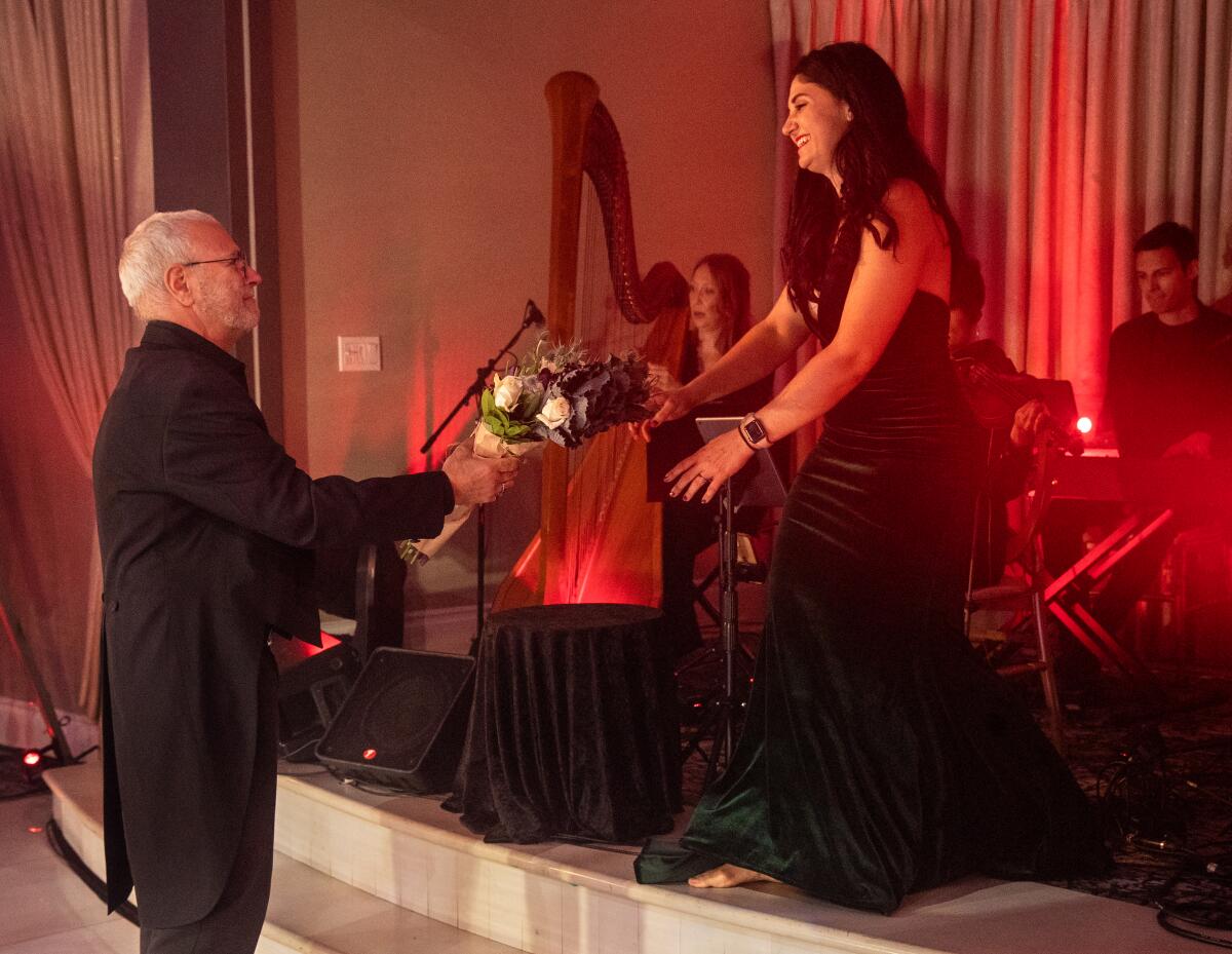 Composer Hummie Mann hands a bouquet of flowers to his daughter near musicians
