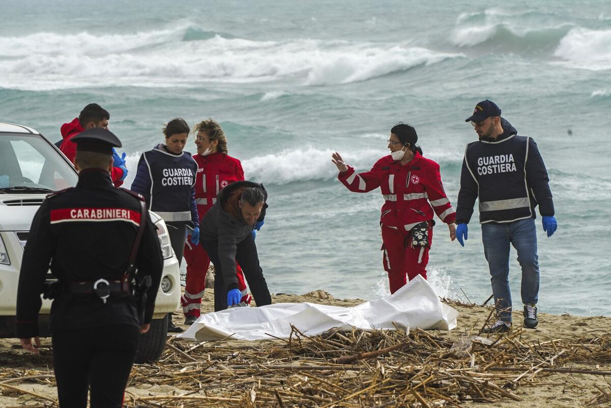 Italian rescue workers with covered body by shore