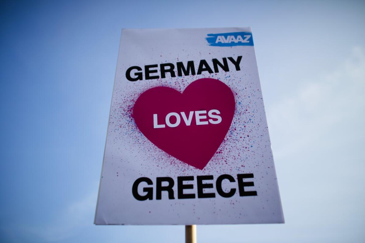 A member of the Avaaz organization displays a poster during a demonstration for German-Greek solidarity before a meeting in Berlin between German Chancellor Angela Merkel and Greek Prime Minister Alexis Tsipras.