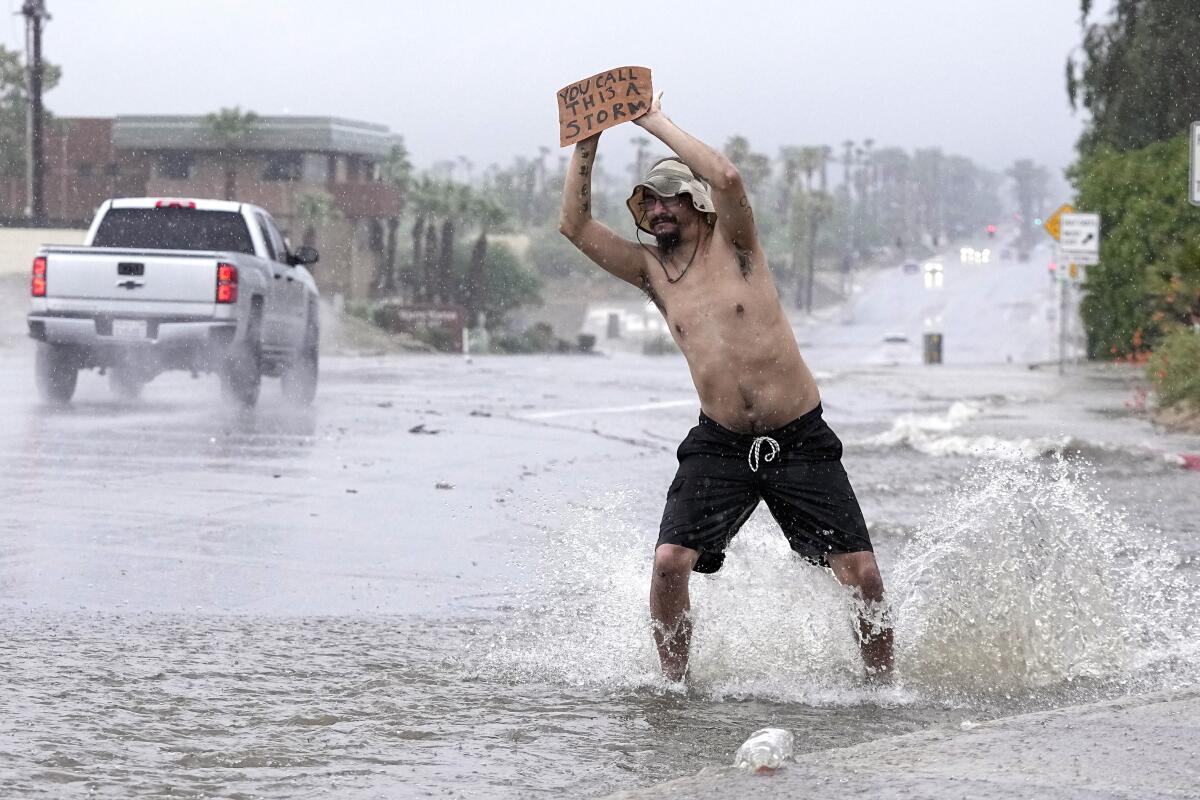A man stands in the street with a sign that says "You call this a storm?"