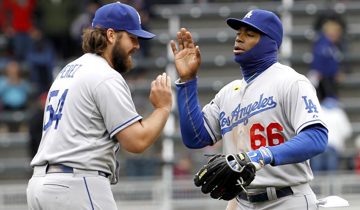 Dodgers relief pitcher Chris Perez (54) and right fielder Yasiel Puig (66) celebreate after defeating the Minnesota Twins in the first game of a doubleheader on Thursday in Minneapolis.