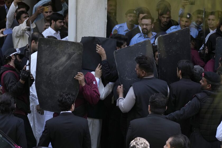 Security personnel with bulletproof shields escort former Prime Minister Imran Khan, center, as he arrives to appear in a court, in Islamabad, Pakistan, Monday, March 27, 2023. A Pakistani court ruled in defense of former Prime Minister Khan, granting him protection from arrest as lawsuits mounted against the ousted premier, with police charging him with incitement to violence in several cases when his followers clashed with the security forces this month. (AP Photo/Anjum Naveed)