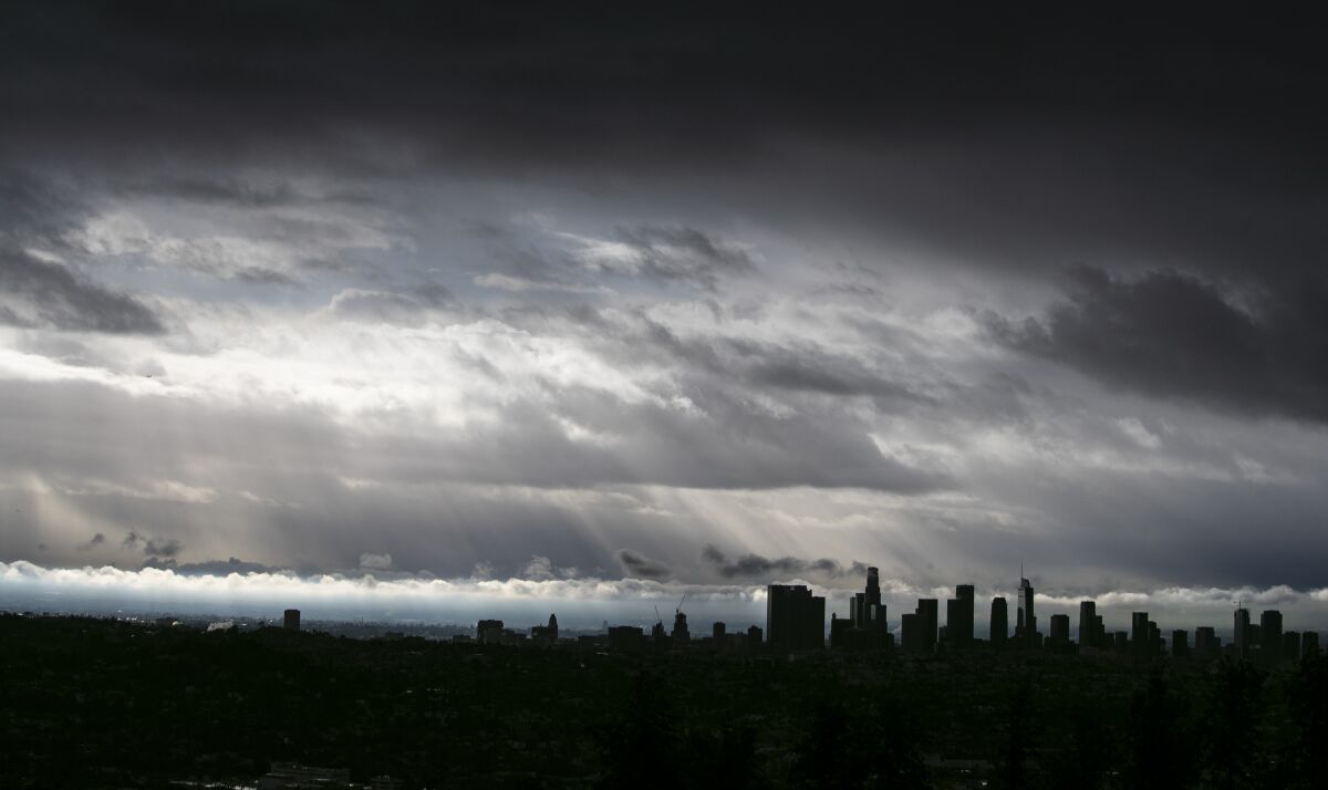 A bank of gray clouds hangs over a darkened Los Angeles skyline.