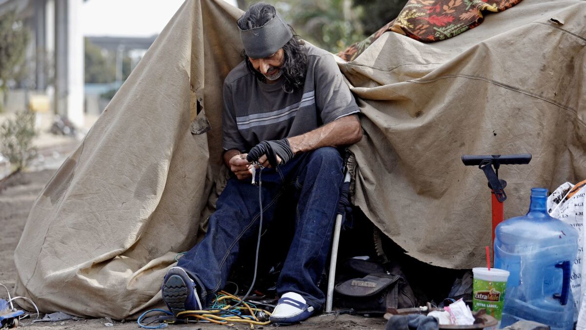 Raul Rodriguez strips wire to sell the copper at a homeless camp along West 117th and South Figueroa streets in Los Angeles.
