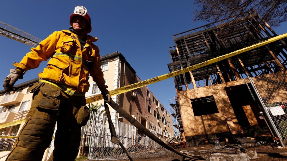 L.A. City Fire captain Tim Gill pulls hoses at the scene in the 400 block of Helitrope Drive in East Hollywood.