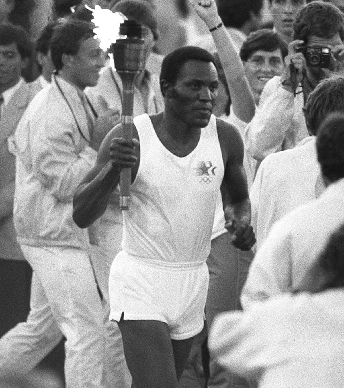 Rafer Johnson runs on the track at the Coliseum on his way to lighting the Olympic flame in 1984.