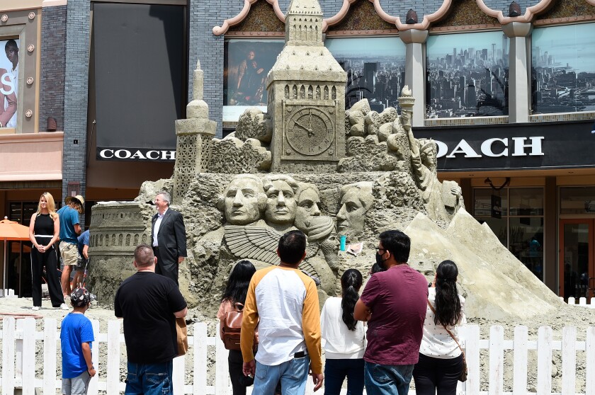 People look at a sand sculpture at the Citadel Outlets