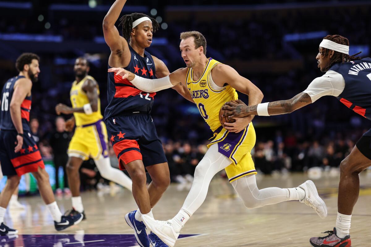 Lakers guardı Luke Kennard (ortada), Washington'dan Tre Johnson (solda) ile Jamir Watkins arasında araba kullanıyor.