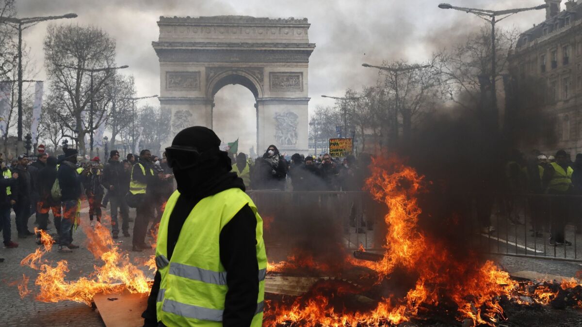 A "yellow vest" protester walks past a fire on the Champs-Elysees on Saturday in Paris.