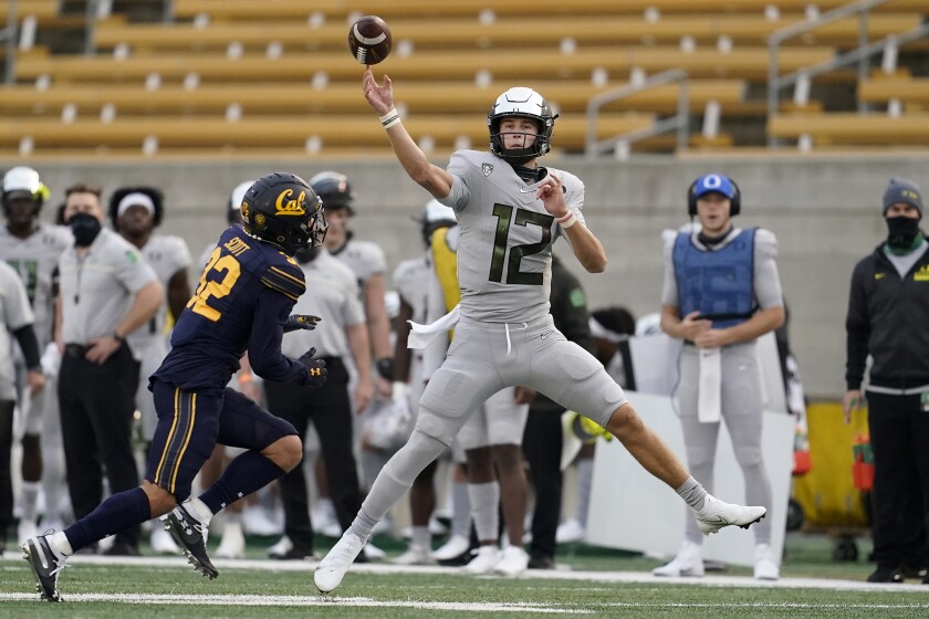 Oregon quarterback Tyler Shough (12) throws a pass as California safety Daniel Scott (32) closes in during the first half of an NCAA college football game in Berkeley, Calif., Saturday, Dec. 5, 2020. (AP Photo/Jeff Chiu)
