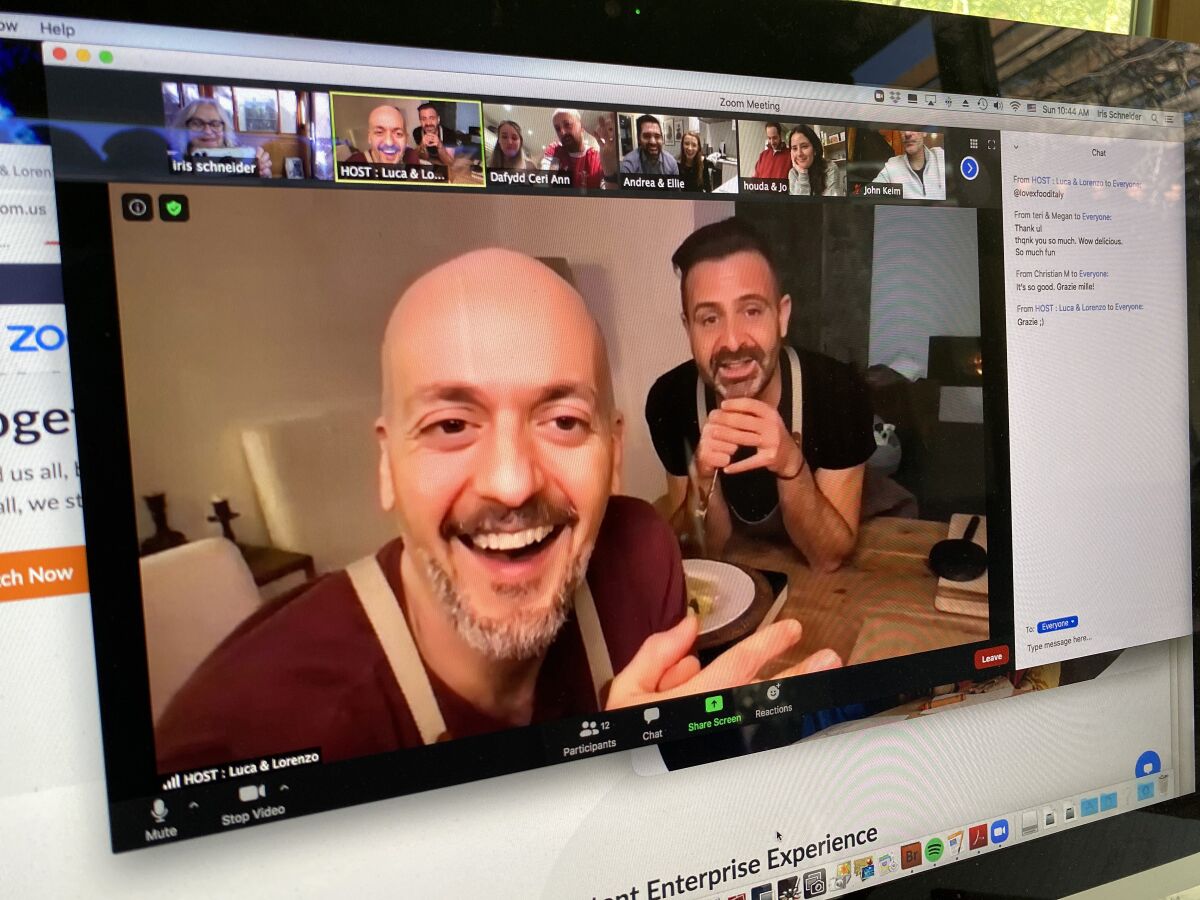 Two smiling men appear in a video open on a computer screen