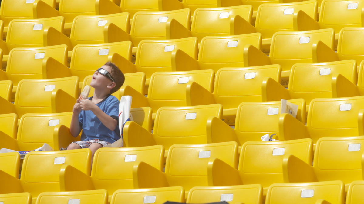 A person sits alone in a field of yellow seats.