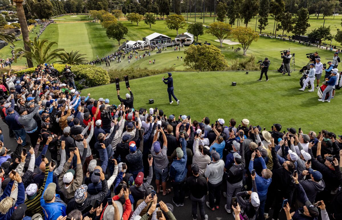 Fans hold up smartphones to capture Tiger Woods as he tees off in the Genesis Invitational at Riviera Country Club.