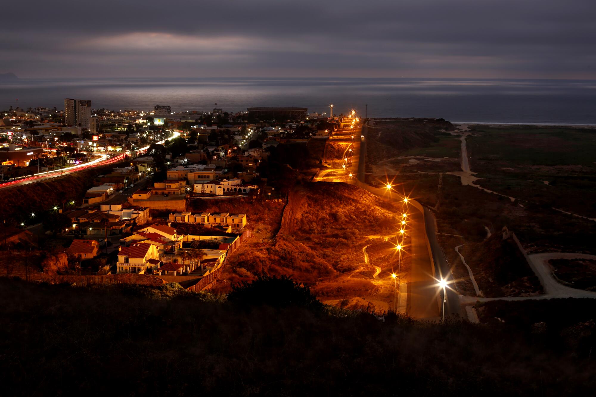Lights show the winding path of double fencing between Tijuana and San Diego after sunset. 