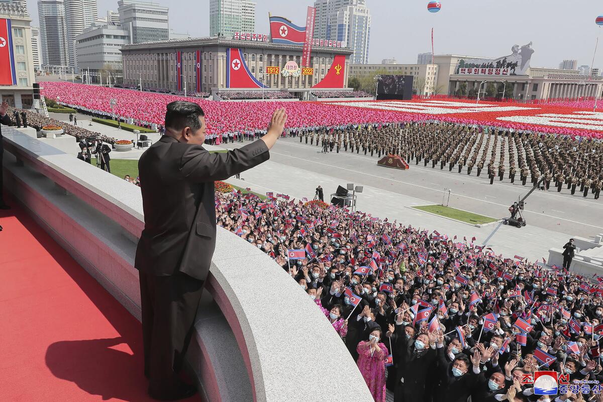 North Korean leader Kim Jong Un attends a parade and waves to a crowd.