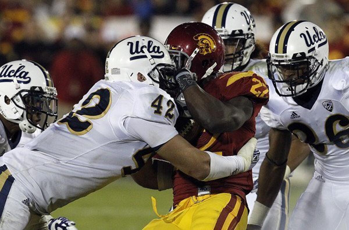USC running back Curtis McNeal is hit by UCLA linebacker Patrick Larimore in their rivalry game last year.