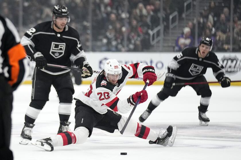 New Jersey Devils center Michael McLeod, center, falls while under pressure from Los Angeles Kings.