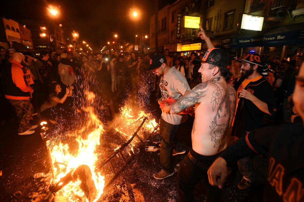 San Francisco Giants fans celebrate next to debris that has been set on fire in the Mission district after the San Francisco Giants beat the Kansas City Royals to win the World Series.