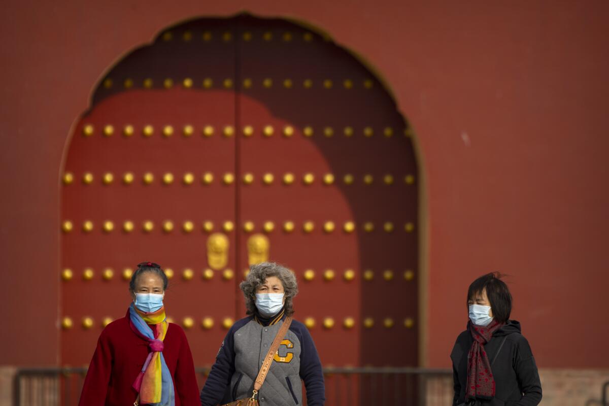 People wearing face masks walk at the Temple of Heaven in Beijing, Saturday, Nov. 12, 2022. 