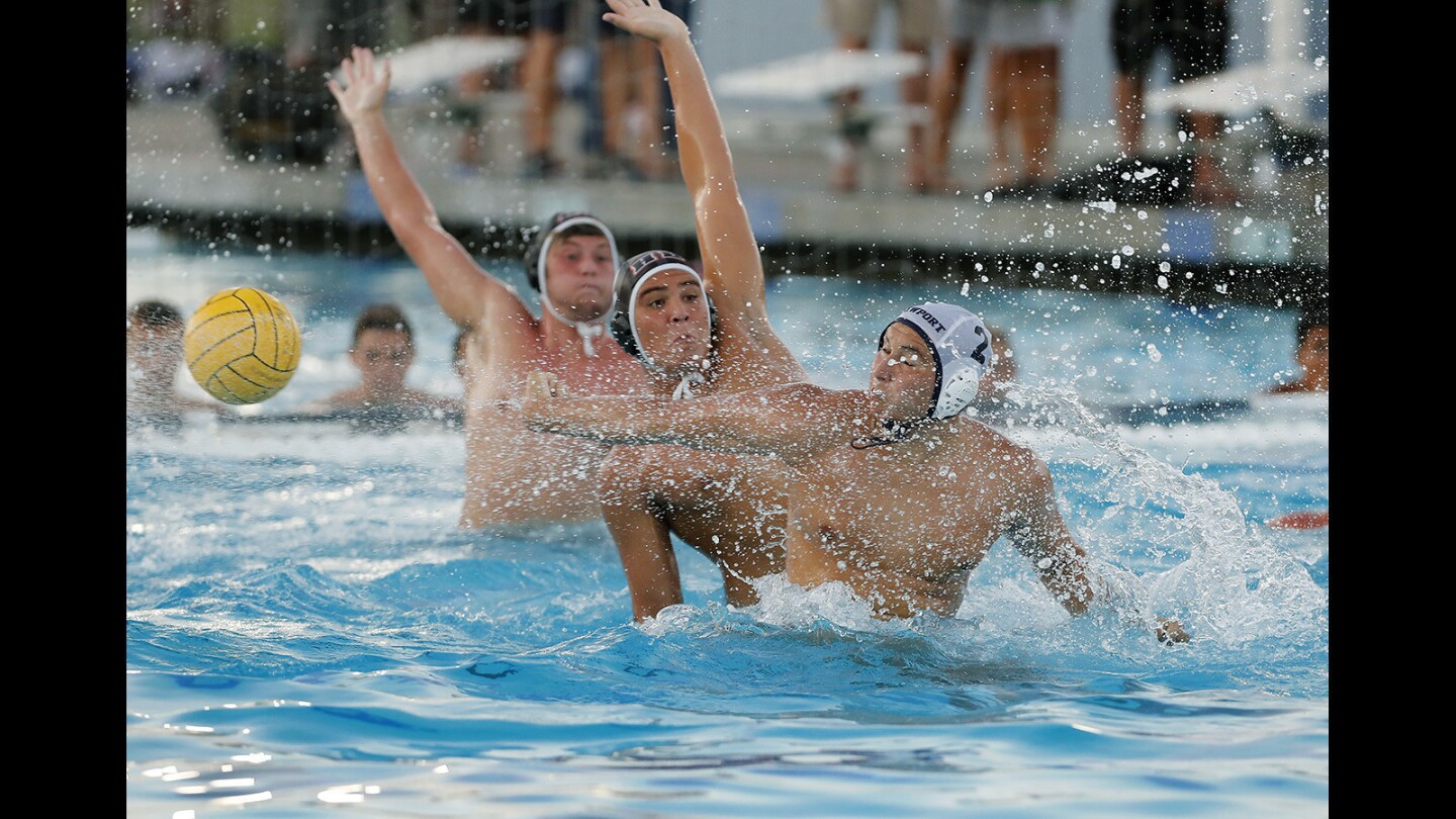 Newport Harbor High's Makoto Kenney, right, forces overtime with this score against Huntington Beach's Garrett Zaan, center, late in the fourth quarter during a Sunset League finale game in Newport Beach on Wednesday, Oct. 25.
