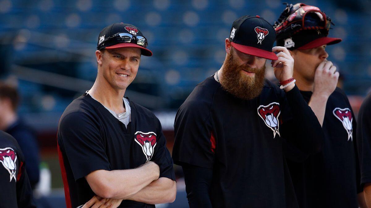 Arizona Diamondbacks starting pitcher Zack Greinke, left, smiles as he talks with relief pitcher Archie Bradley, right, during practice on Monday at Chase Field as the team gets ready for a National League wild card game.