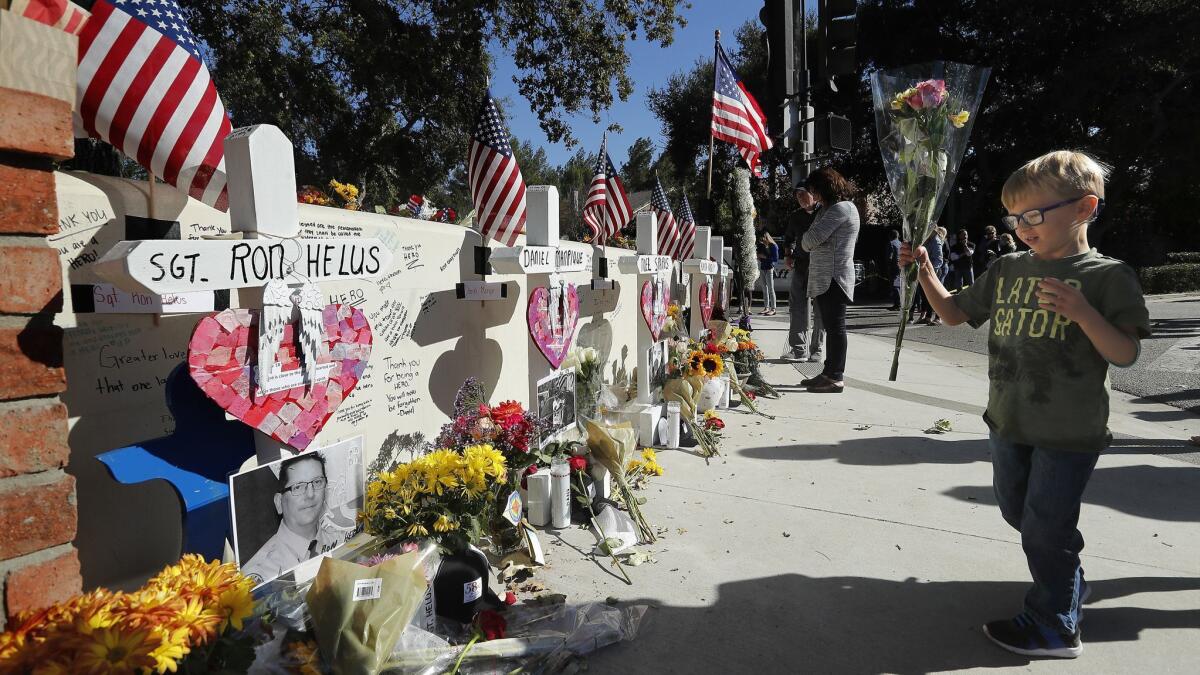 Ben Alexander, 4, of Westlake Village places flowers next to each cross at a makeshift memorial for victims of the Borderline Bar and Grill shooting outside the bar.