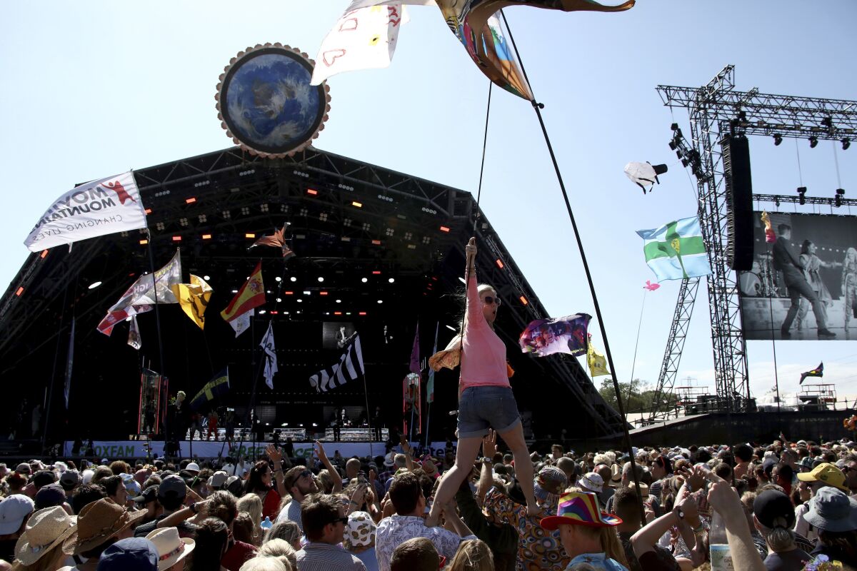 FILE - In this Sunday, June 30, 2019 file photo, revelers react to Kylie Minogue as she performs at the Glastonbury Festival, Somerset, England. Organizers of live events in the U.K., such as festivals and theaters, have given their partial support to a new coronavirus-related insurance initiative aimed at easing their financial worries. In a statement late Thursday, Aug. 5, 2021 the government said it was backing a 750 million-pound ($1 billion) insurance scheme that will cover the cancellation costs incurred by the hard-hit live events sector in the event of further lockdowns in the year from Sept. (Photo by Grant Pollard/Invision/AP, File)