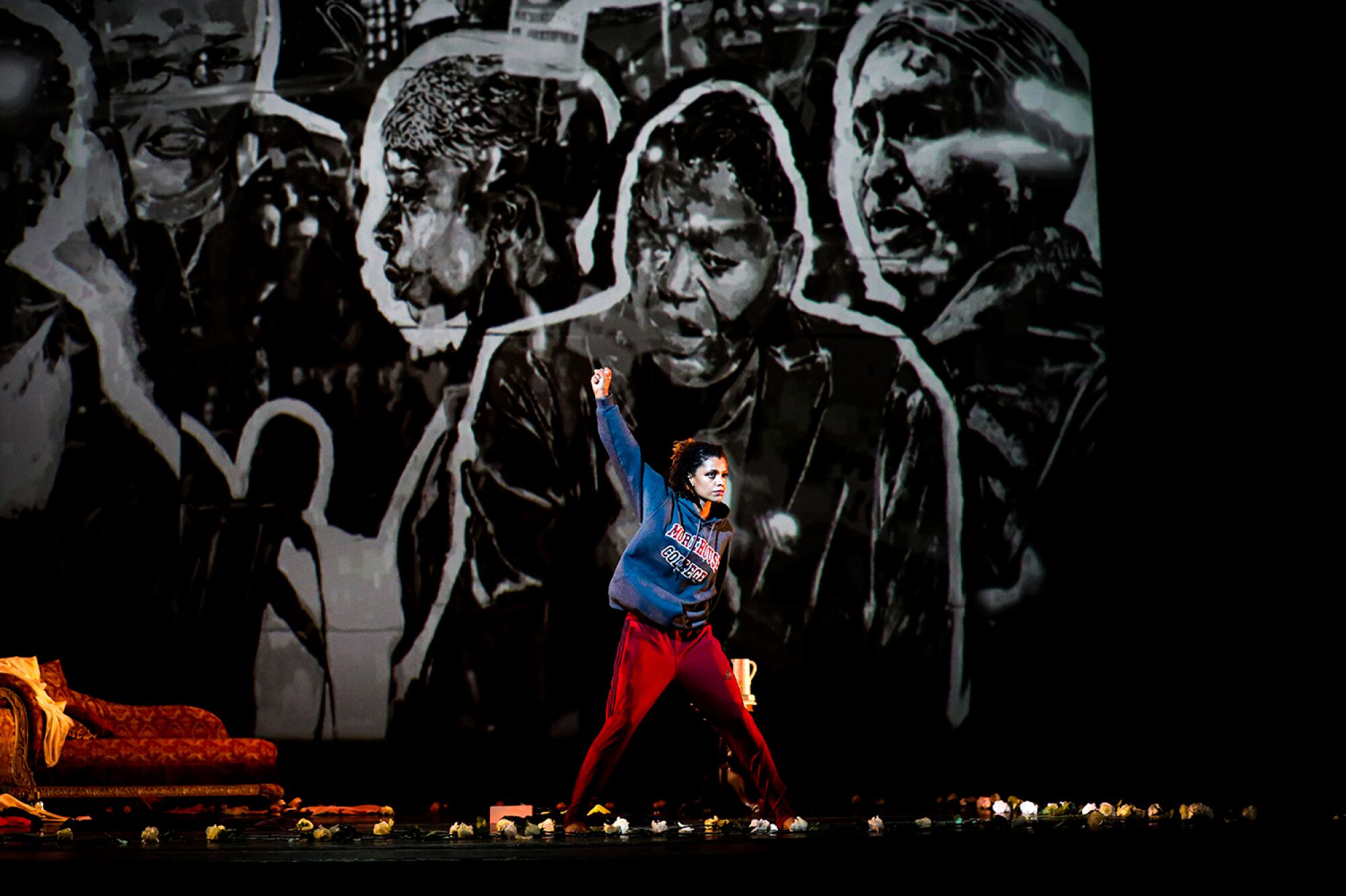 Dancer Fana Tesfagiorgis in “A Mother’s Rite,” with portraits in the background by visual artist Sophia Dawson.