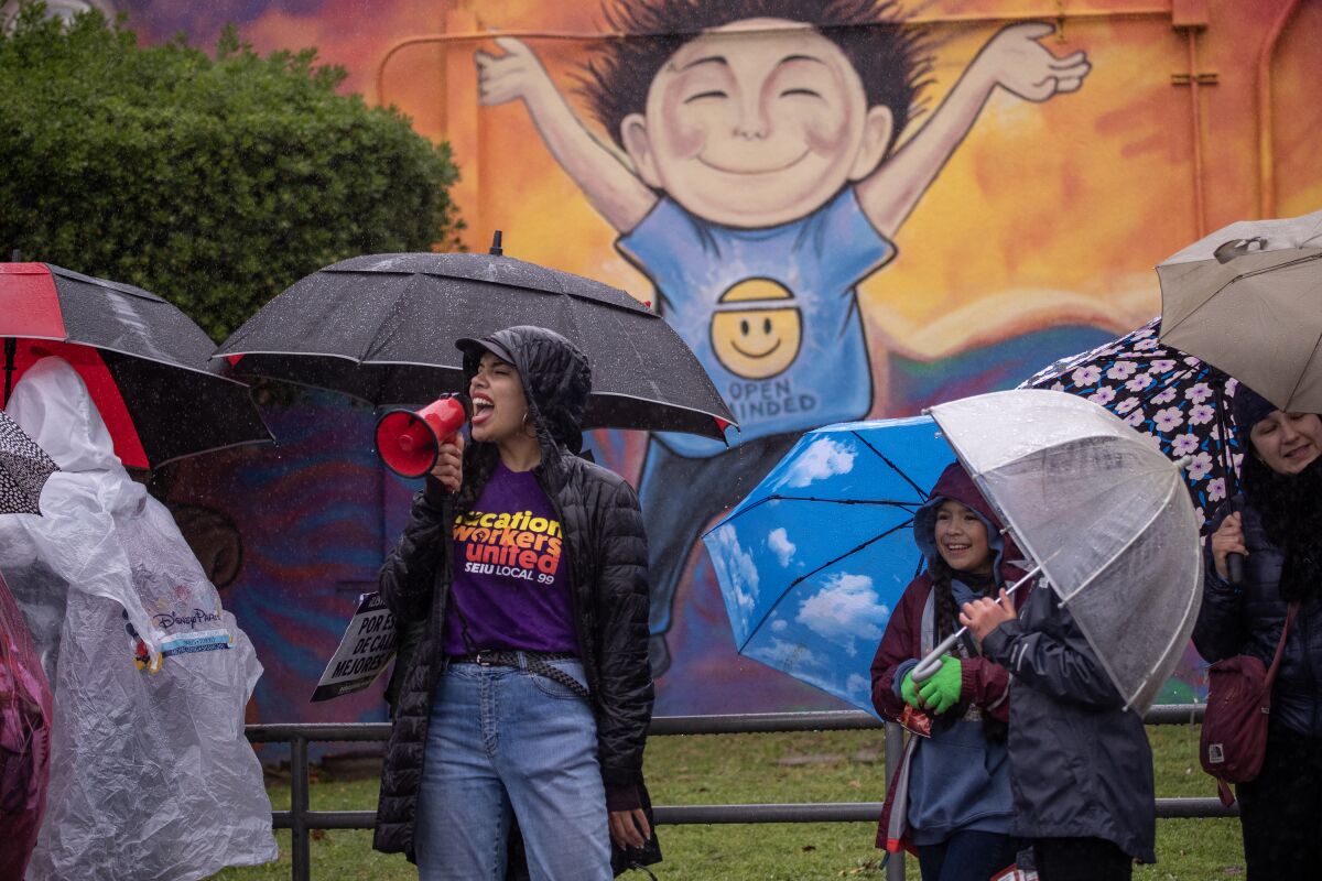 School employees and students strike in the rain in front of a mural at Farmdale Elementary School in El Sereno.
