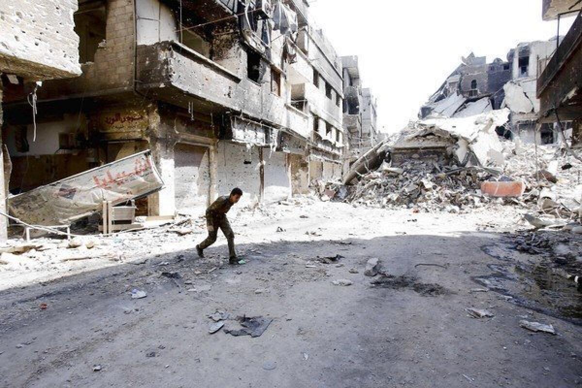 A fighter allied with Syrian President Bashar Assad's government runs through a refugee camp in Damascus last week.