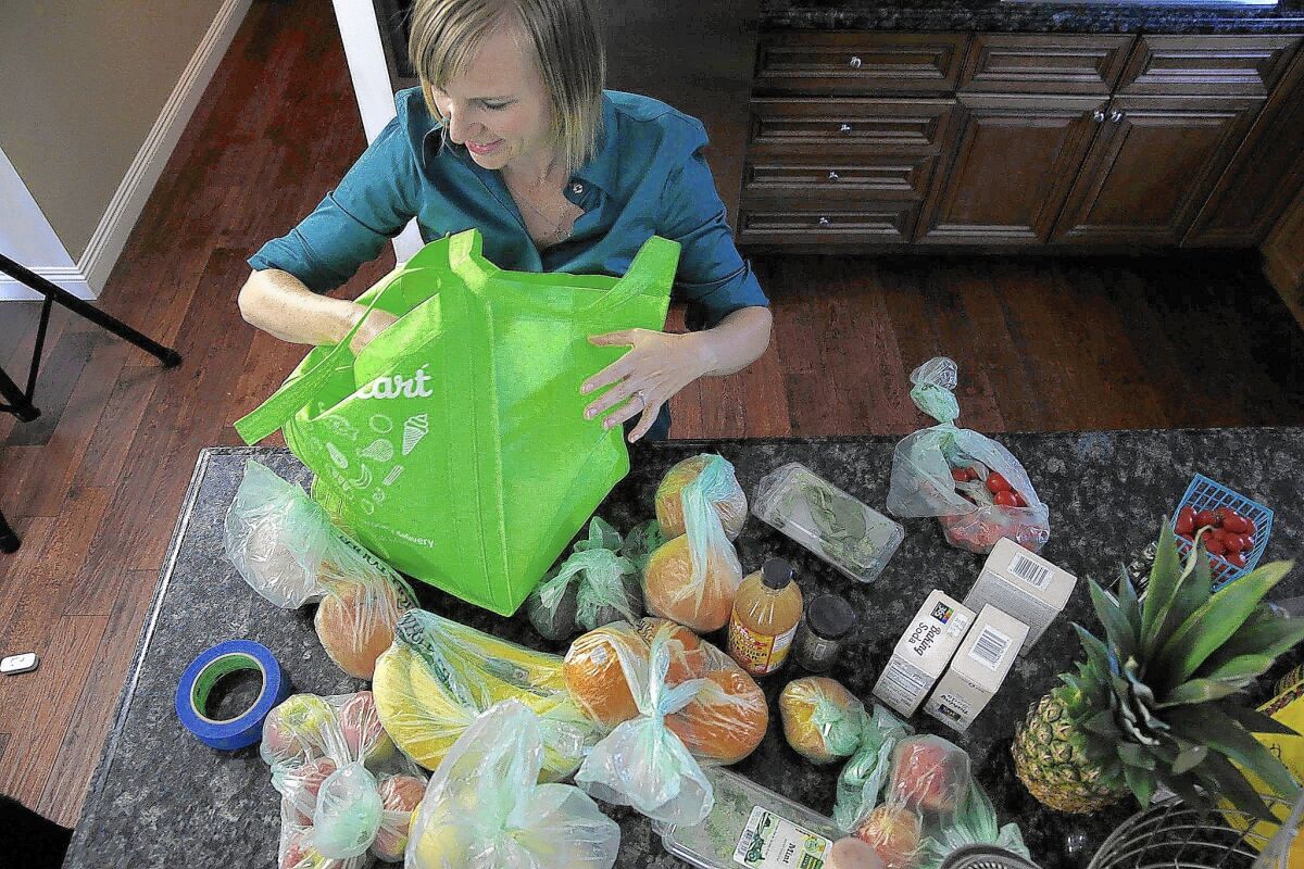Burbank resident Tricia Carr unloads bags of groceries she ordered through delivery service Instacart. A new study says many consumers will keep using such services even after the pandemic ends.