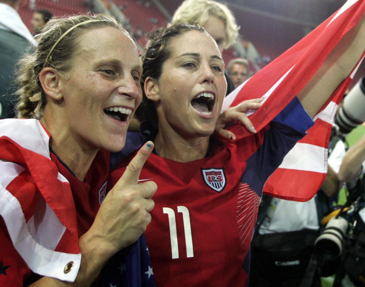 U.S. midfielder and captain Julie Foudy and teammates hold up flags and celebrate winning the 2004 Olympic gold medal