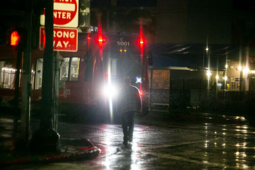 A man crosses paths with the trolley in downtown San Diego on April 6, 2020 in San Diego, California. The streets are largely empty due to the coronavirus outbreak.